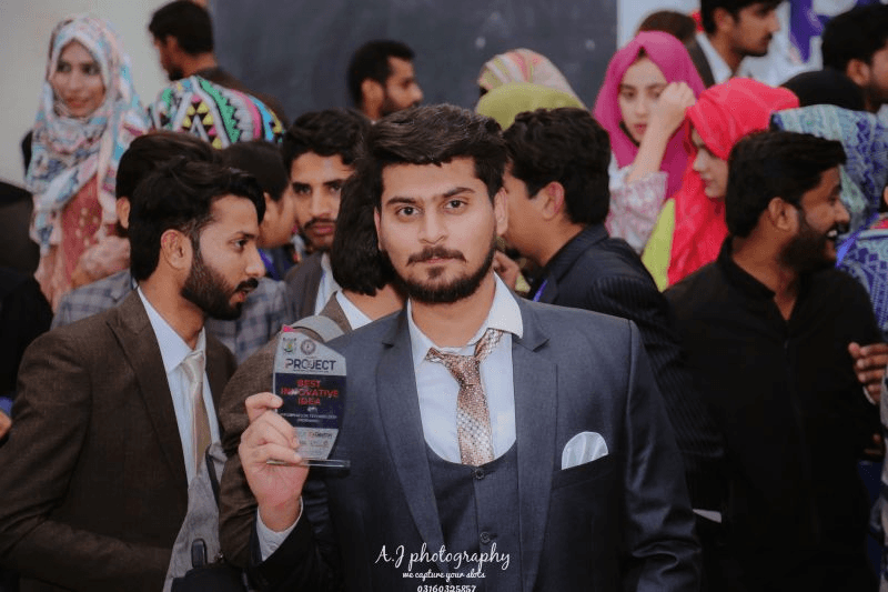 Junaid holding the Best Innovative Idea trophy